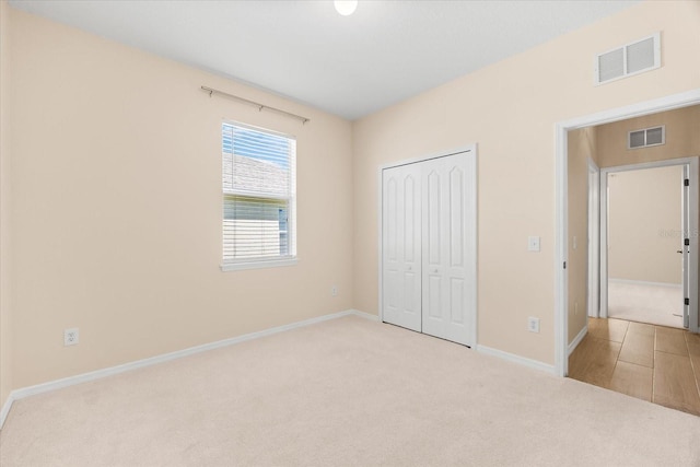 unfurnished bedroom featuring carpet flooring, a closet, visible vents, and baseboards