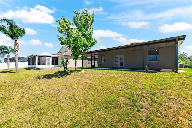 back of property with a sunroom, a lawn, and fence