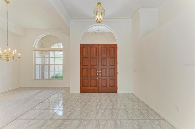 entryway with baseboards, ornamental molding, and a notable chandelier