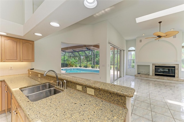 kitchen featuring light stone counters, a sink, light brown cabinets, and a fireplace