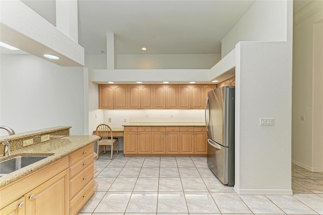 kitchen with freestanding refrigerator, light stone countertops, recessed lighting, a sink, and light tile patterned floors