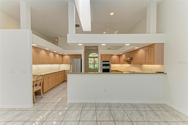 kitchen featuring a peninsula, tasteful backsplash, light stone countertops, and stainless steel appliances