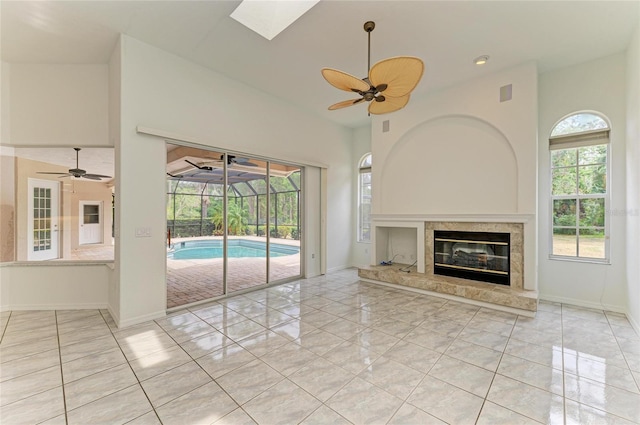 unfurnished living room with baseboards, ceiling fan, a premium fireplace, and a wealth of natural light