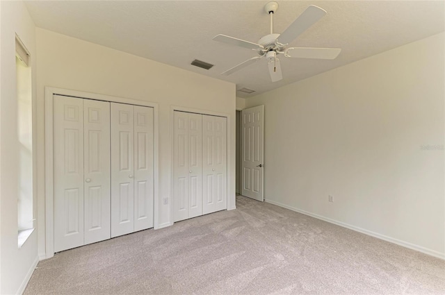 unfurnished bedroom with multiple closets, baseboards, carpet flooring, and visible vents