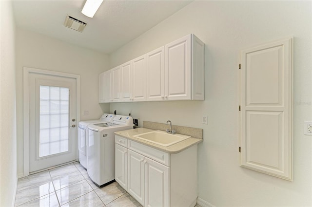 washroom with a sink, washing machine and dryer, cabinet space, and visible vents