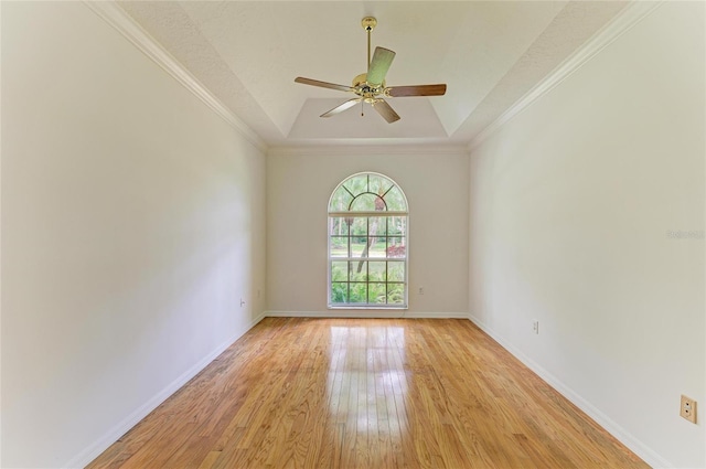 unfurnished room featuring baseboards, ceiling fan, a tray ceiling, and light wood-type flooring