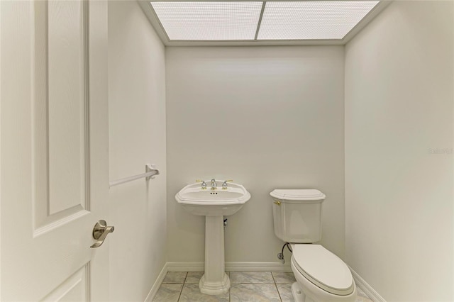 bathroom featuring baseboards, tile patterned floors, and toilet