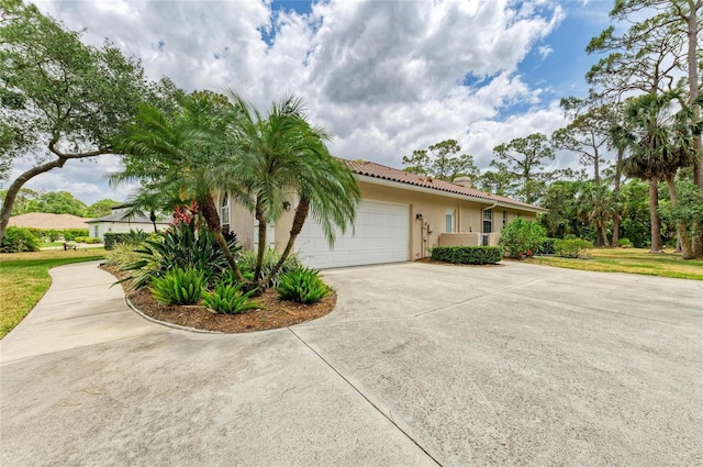 view of home's exterior featuring a garage, stucco siding, a tile roof, and concrete driveway