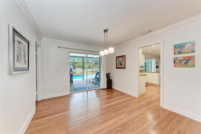 unfurnished dining area with light wood finished floors, crown molding, visible vents, baseboards, and a textured ceiling