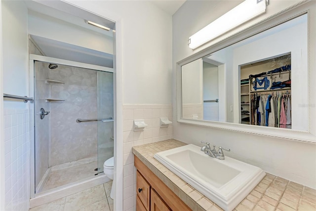 full bathroom with vanity, toilet, a stall shower, and tile walls