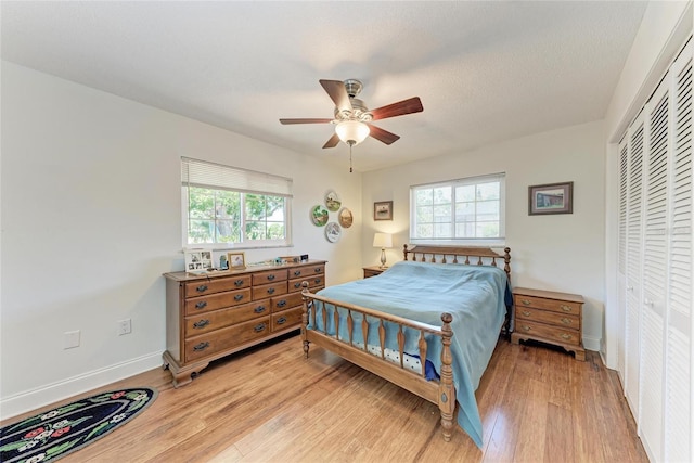 bedroom with baseboards, light wood-type flooring, ceiling fan, and a closet