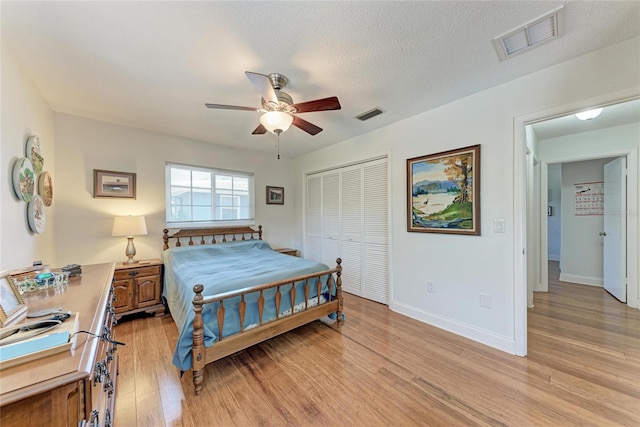 bedroom featuring baseboards, visible vents, light wood-type flooring, and a closet