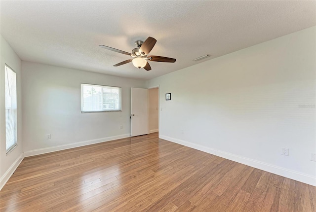 spare room featuring visible vents, ceiling fan, light wood finished floors, and baseboards