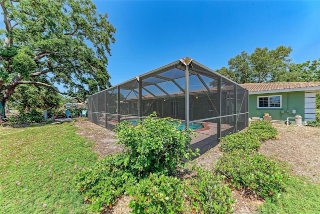 rear view of house with a lawn, an outdoor pool, a patio area, and stucco siding