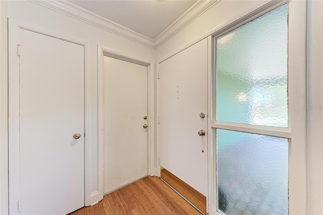 doorway with light wood-style floors and crown molding
