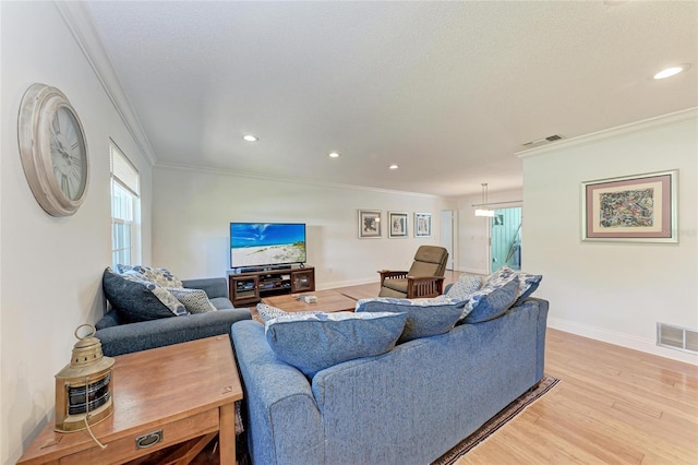living room with visible vents, ornamental molding, and light wood-style flooring