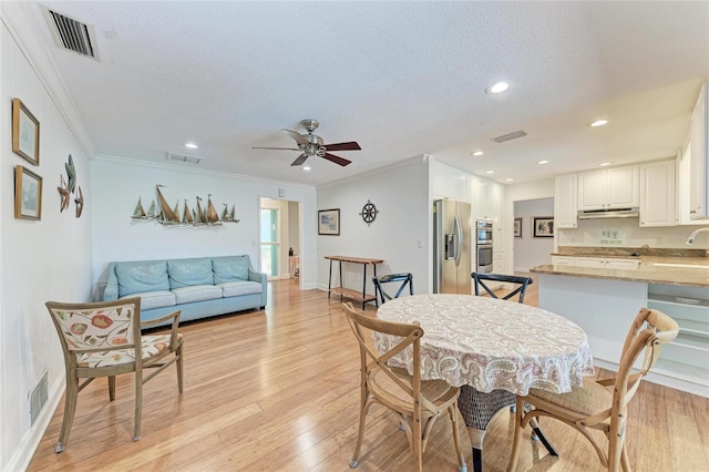 dining room with crown molding, a textured ceiling, visible vents, and a ceiling fan
