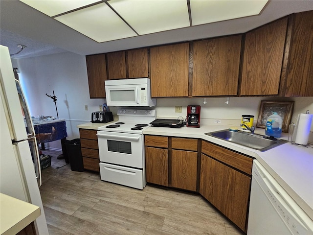kitchen with a sink, white appliances, and light countertops