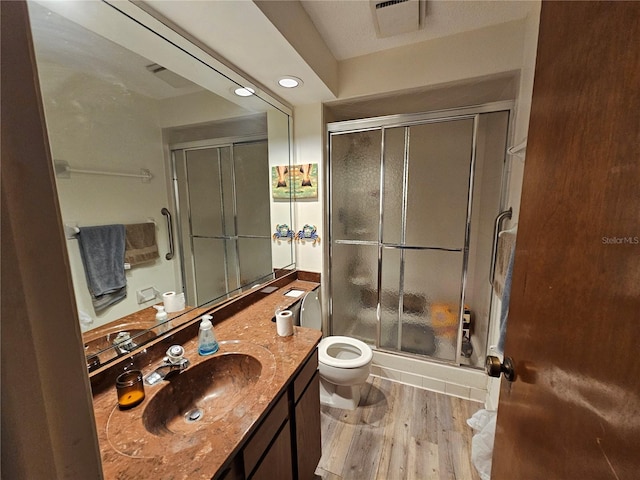 bathroom with toilet, a stall shower, visible vents, wood finished floors, and vanity