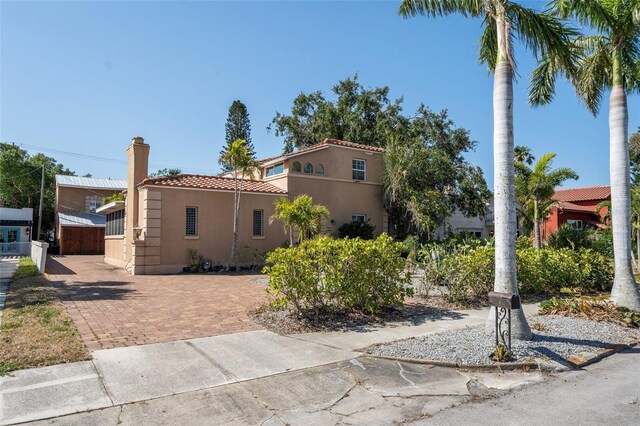 view of front facade with a chimney, a tile roof, and stucco siding