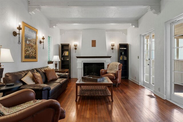 living area with a fireplace, hardwood / wood-style floors, baseboards, beamed ceiling, and visible vents