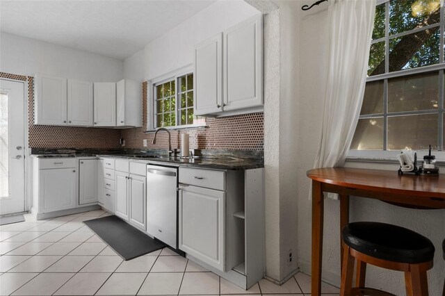 kitchen with light tile patterned flooring, tasteful backsplash, a sink, and dishwasher