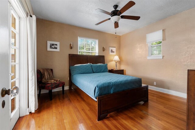 bedroom with baseboards, a textured ceiling, and light wood-style flooring