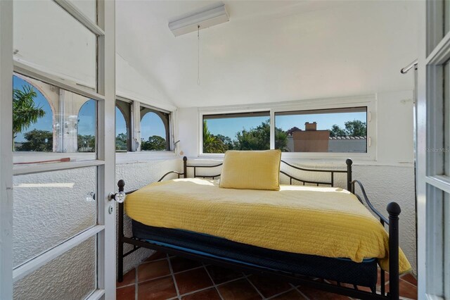 tiled bedroom featuring multiple windows and lofted ceiling