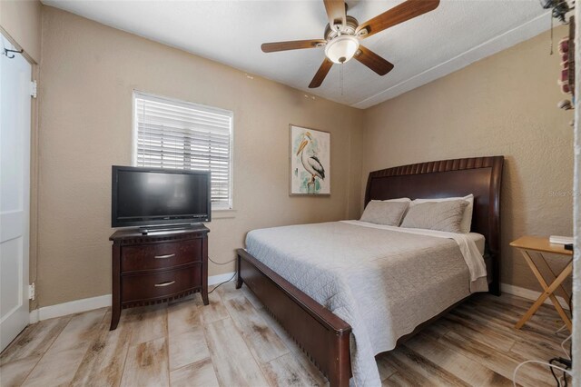 bedroom featuring baseboards, light wood finished floors, and ceiling fan