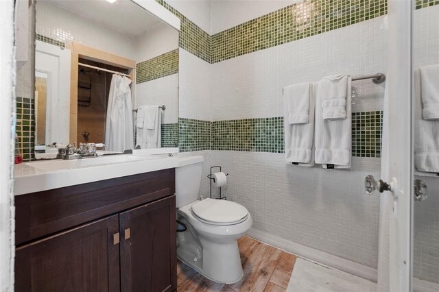 bathroom with vanity, toilet, a shower with shower curtain, tile walls, and wood finished floors