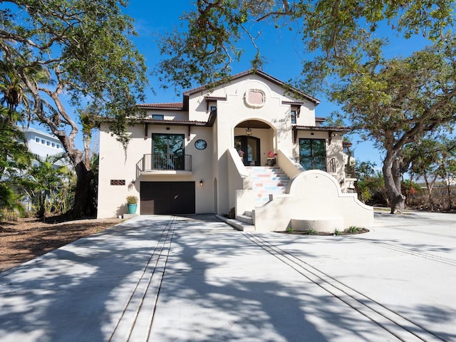 mediterranean / spanish-style house with stucco siding, a garage, a tile roof, a balcony, and concrete driveway