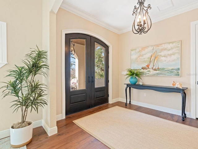 entryway with arched walkways, wood finished floors, french doors, and crown molding
