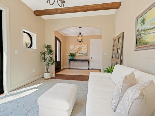 living area with beam ceiling, a chandelier, baseboards, arched walkways, and wood finished floors