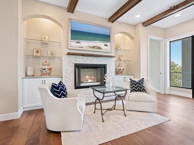 living room featuring recessed lighting, wood finished floors, beamed ceiling, baseboards, and a lit fireplace