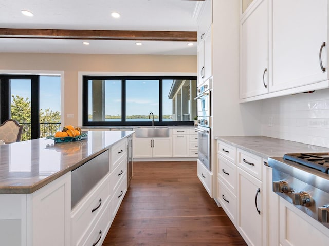 kitchen featuring beam ceiling, a healthy amount of sunlight, appliances with stainless steel finishes, and a sink