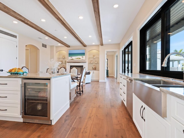 bar featuring beam ceiling, beverage cooler, arched walkways, and a sink