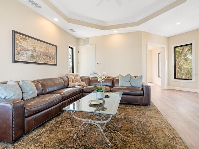 living area featuring visible vents, wood finished floors, crown molding, and a tray ceiling