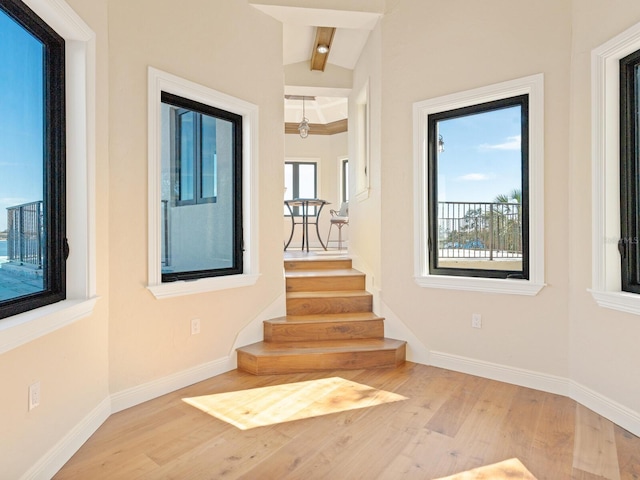 stairs with beam ceiling, wood finished floors, and baseboards