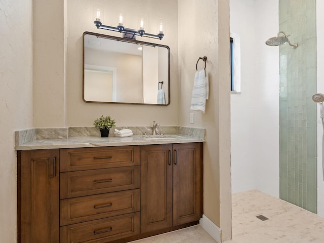 full bath featuring a tile shower, tile patterned flooring, and vanity
