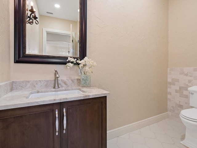 bathroom featuring visible vents, toilet, vanity, and baseboards