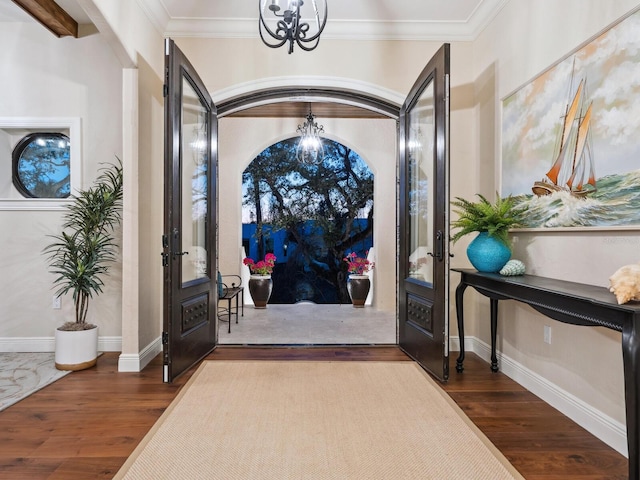 entryway with ornamental molding, dark wood-style floors, and a chandelier