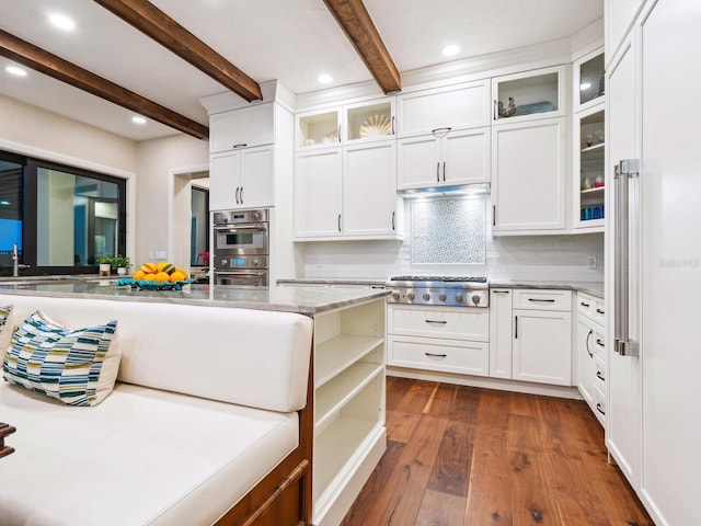 kitchen with beam ceiling, light stone counters, white cabinets, appliances with stainless steel finishes, and dark wood finished floors