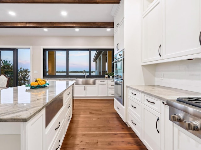 kitchen with white cabinetry, stainless steel appliances, beamed ceiling, and a sink