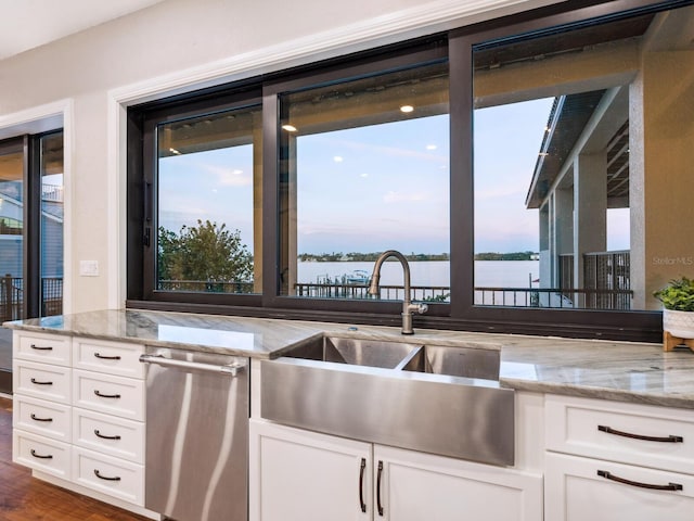 kitchen with white cabinets, light stone counters, and a sink