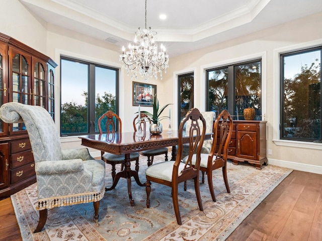 dining room with light wood-style floors, a notable chandelier, a tray ceiling, visible vents, and baseboards