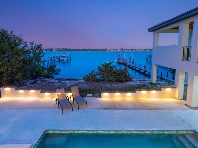 view of pool featuring a dock, a patio area, and a water view