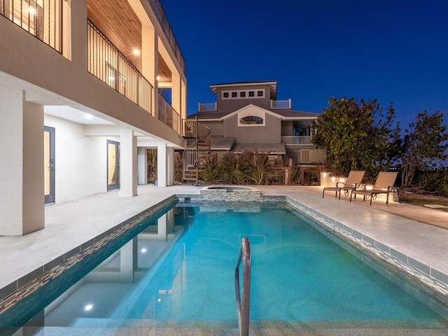 pool at twilight featuring a patio area, a pool with connected hot tub, and stairs
