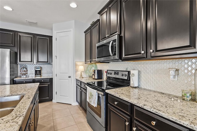 kitchen with appliances with stainless steel finishes, backsplash, light stone counters, and visible vents