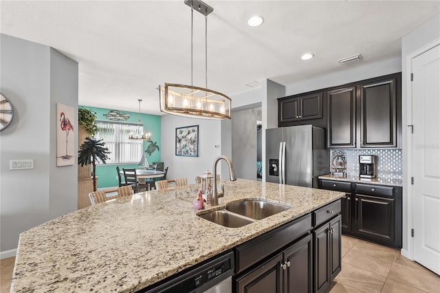 kitchen with light stone countertops, appliances with stainless steel finishes, a sink, a chandelier, and visible vents