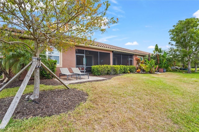 rear view of property with a tiled roof, a lawn, a sunroom, a patio, and stucco siding